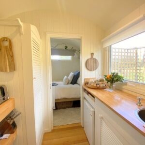 Eco-friendly farmstay hut with wooden exterior surrounded by farmland and nature reserves.