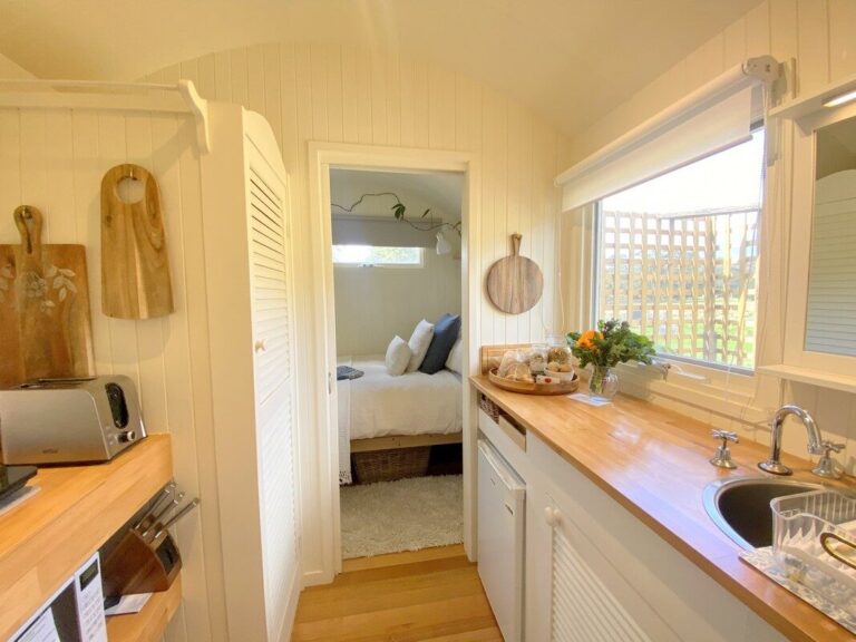 Eco-friendly farmstay hut with wooden exterior surrounded by farmland and nature reserves.